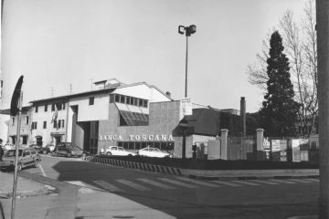 Piazza IV Novembre, anni ‘70-’80. Il vecchio palazzo Melani, sede delle Suore Mantellate, che fu abbandonato negli anni ‘50 a seguito dell’edificazione del nuovo istituto intitolato a Mario Baldi, fu ridotto ad appartamenti privati. Negli anni ‘70 una parte fu comprata dalla Banca Toscana, che demolì in parte per ricostruire l’edificio in forme moderne alquanto discutibili. A fianco si nota ancora il vecchio cancello delle suore che era caratterizzato dallo stemma dell’ordine dei Servi di Maria.